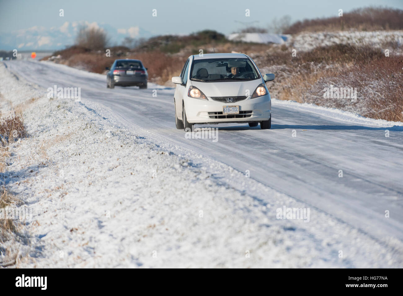 Cars driving in direzioni opposte verso il basso una strada ghiacciata. Foto Stock
