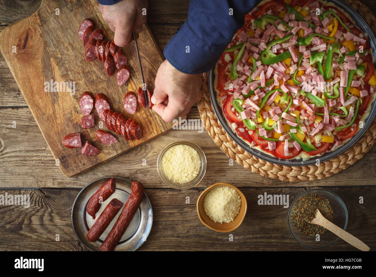 L'uomo tagliare la salsiccia pizza sul bordo orizzontale Foto Stock