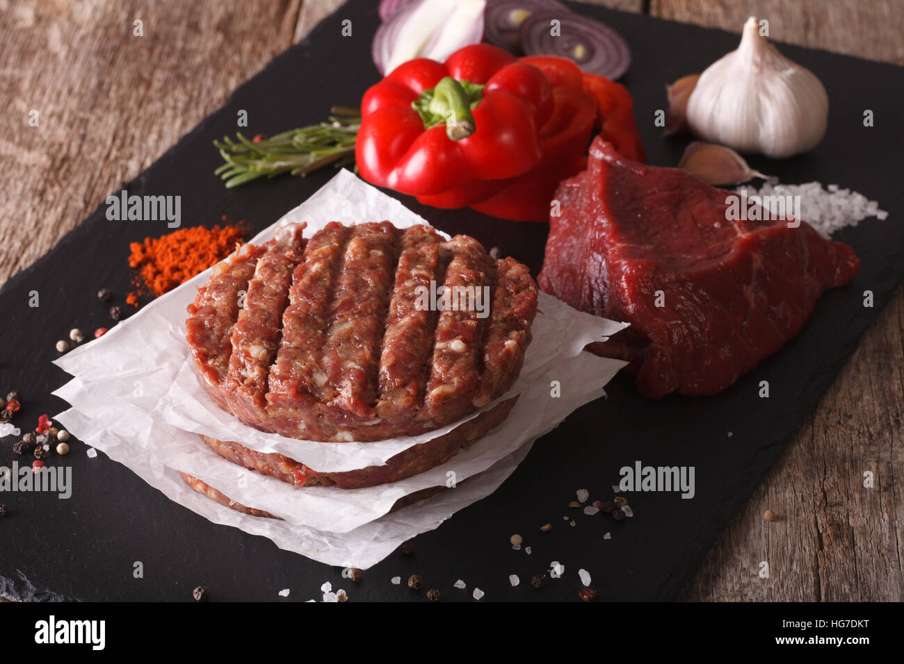 Materie di macinato di manzo hamburger di carne costolette di manzo con ingredienti sulla scheda. Primo piano orizzontale Foto Stock