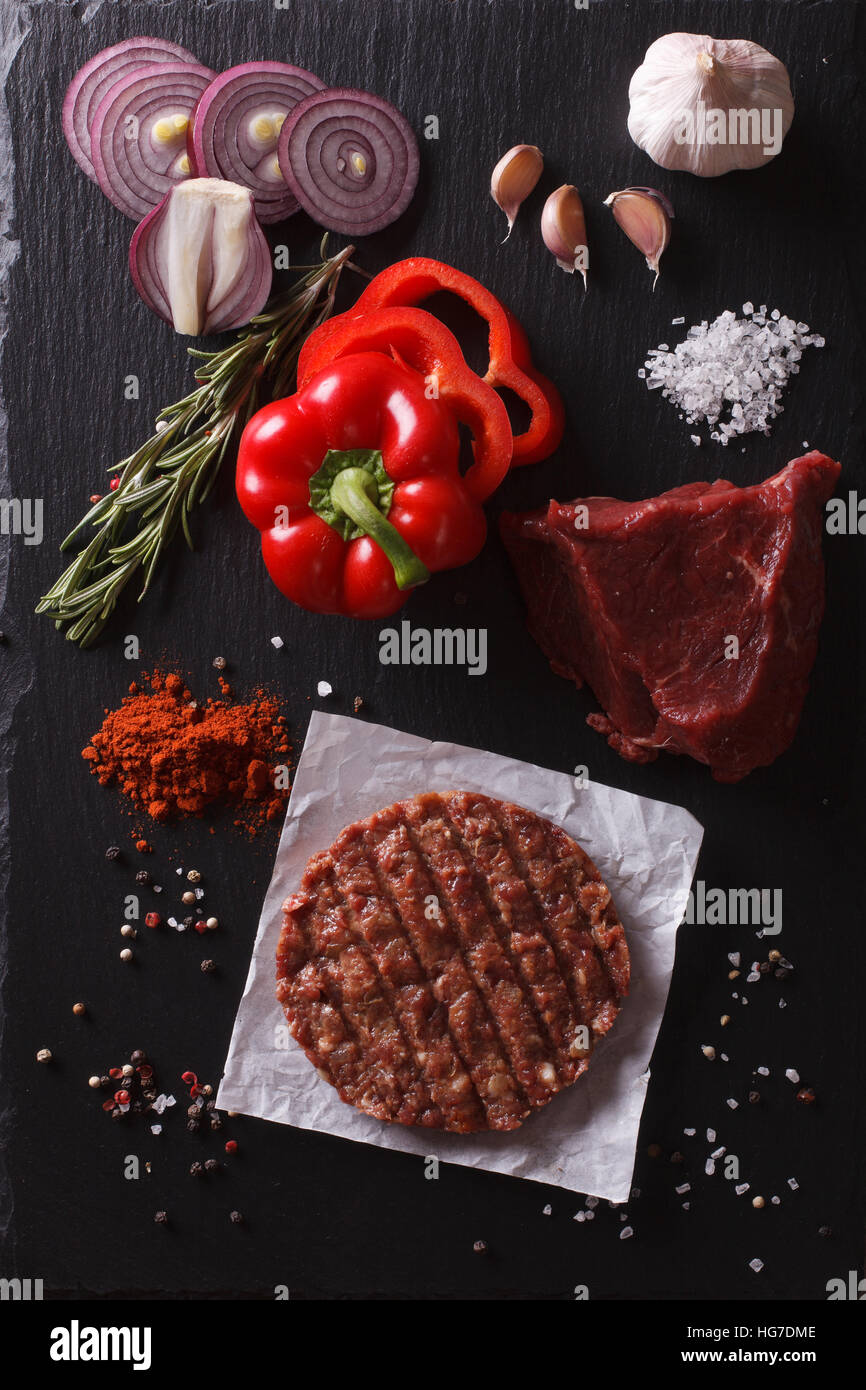 Materie di macinato di manzo hamburger di carne costolette di manzo con ingredienti sulla scheda. vista verticale da sopra Foto Stock