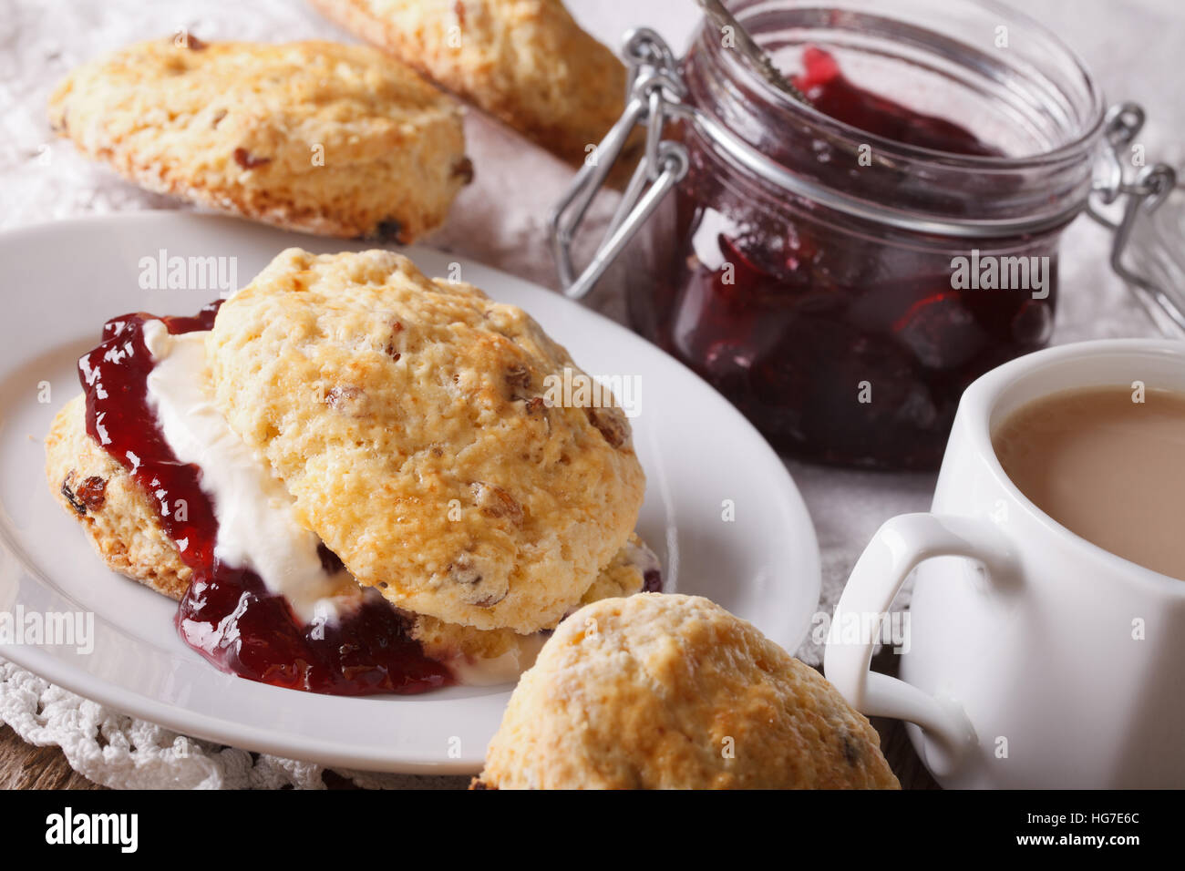 Pasticceria inglese: scones con marmellata e tè con latte vicino sul tavolo. Posizione orizzontale Foto Stock