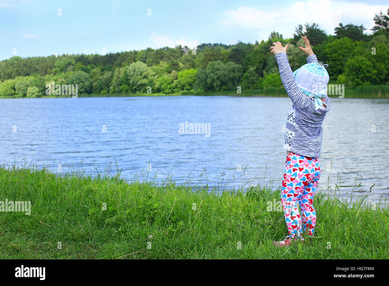 Bambino indica qualcosa di vicino al fiume sull'erba verde Foto Stock