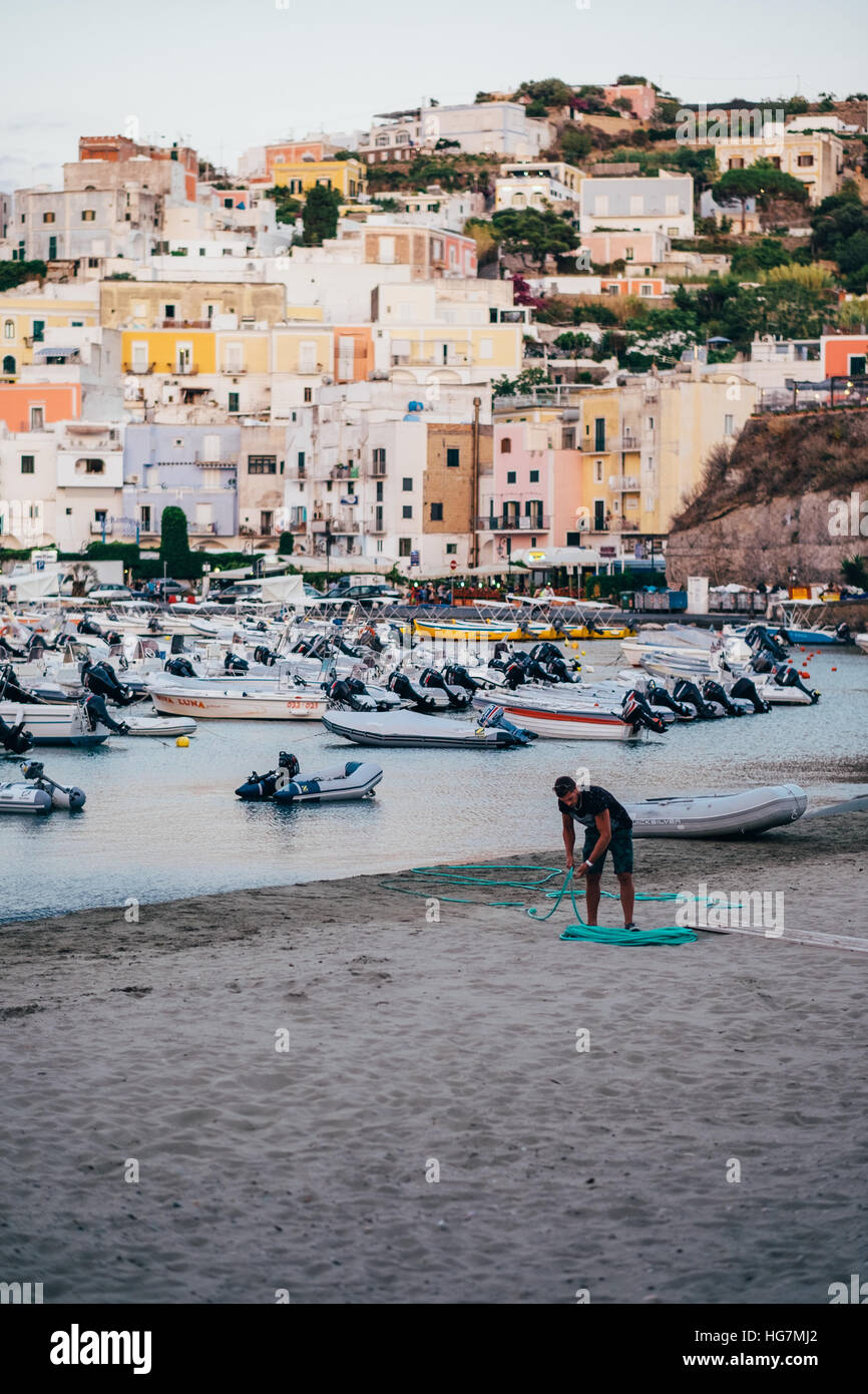 Un uomo bobine un flessibile sulla spiaggia dopo che il sole ha impostato sull'isola di Ponza, Italia. Foto Stock