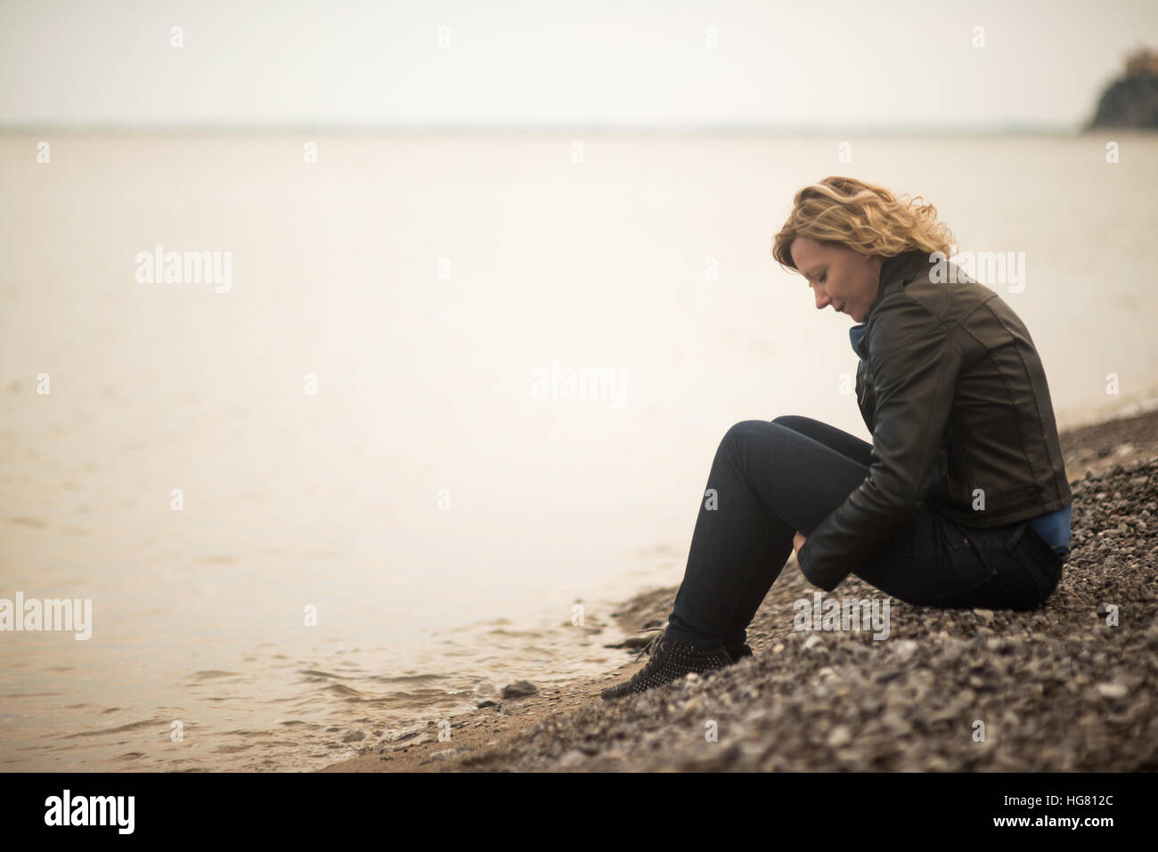 Malinconici donna fantasticando in riva al mare Foto Stock