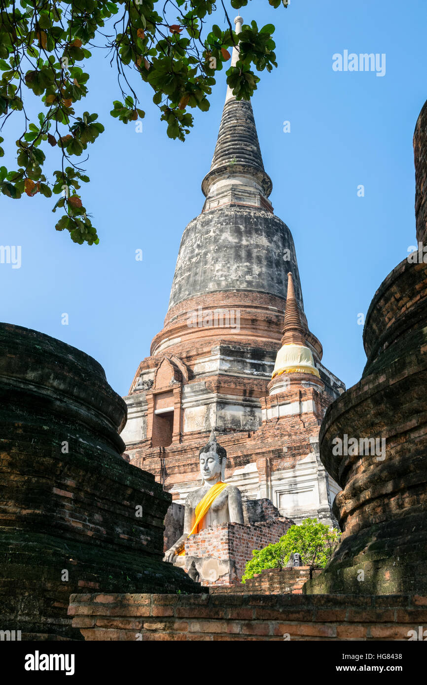 Statua di Buddha in corrispondenza del fondo di un antico e grande pagoda in cielo blu sullo sfondo di Wat Yai Chai Mongkon tempio di Phra Nakhon Si Ayutthaya storico Foto Stock