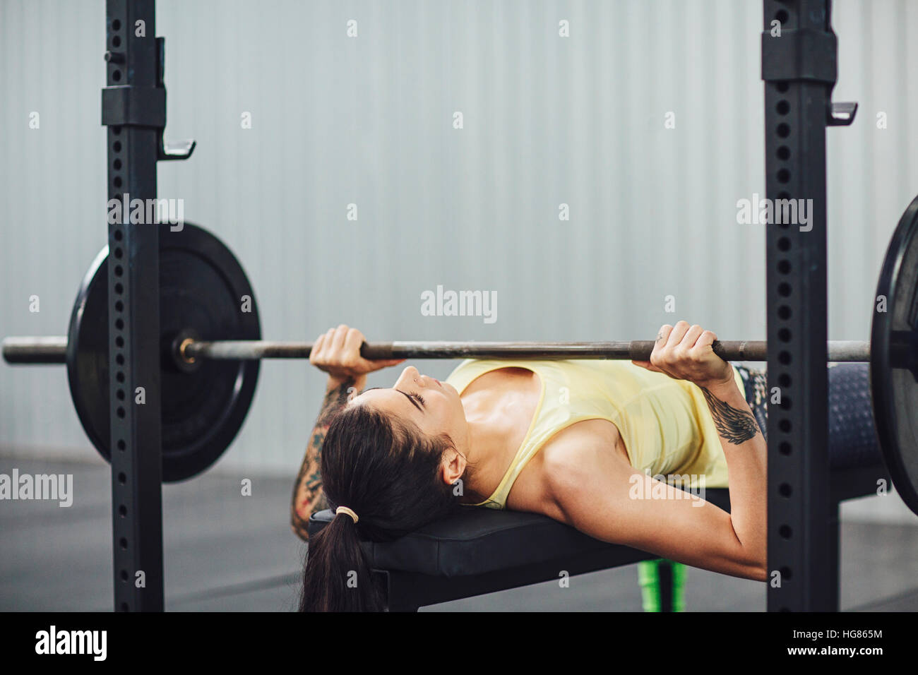 Donna facendo la pressa da banco in palestra Foto Stock