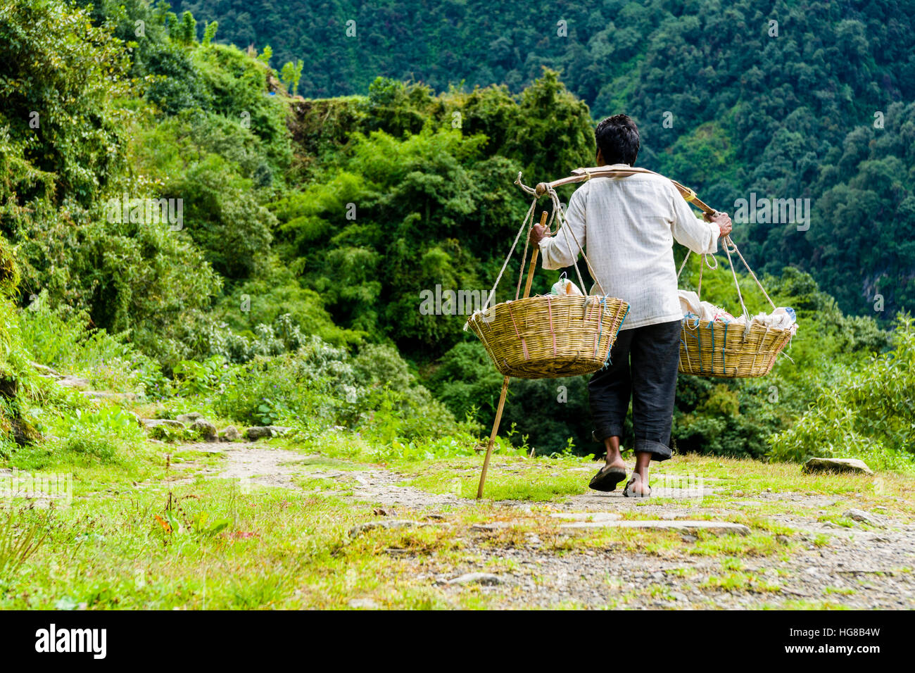 L uomo è il trasporto di merci lungo una pista, Chomrong, Kaski District, Nepal Foto Stock
