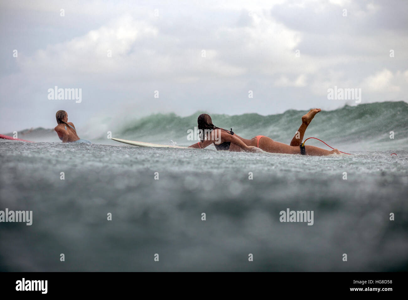 Amici giacente sulla tavola da surf durante la navigazione in mare durante la stagione delle piogge Foto Stock