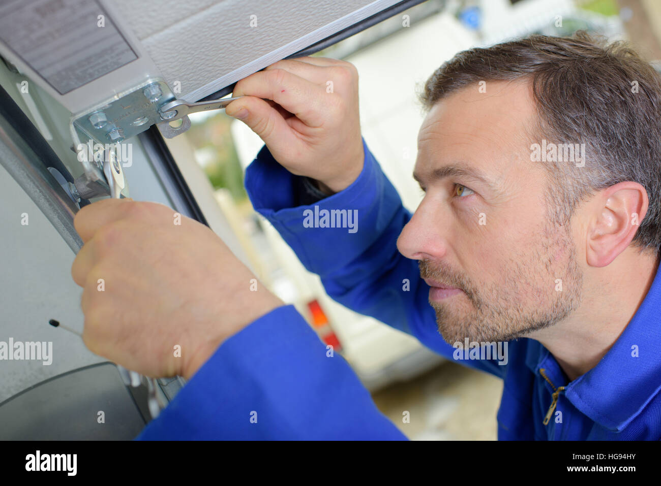 L'uomo l'installazione di una porta di garage Foto Stock