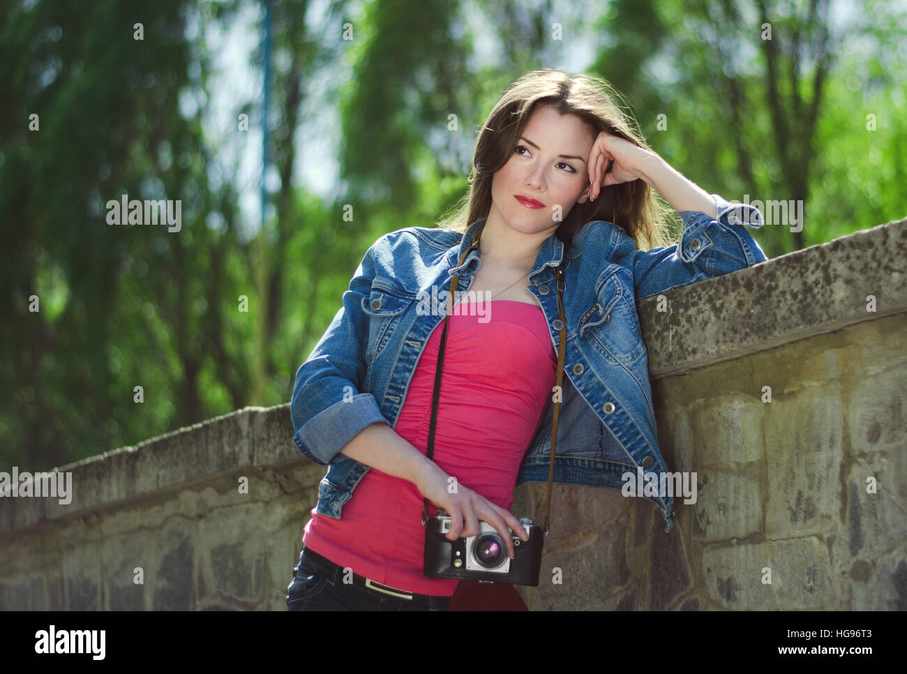 Ragazza giovane con una vecchia macchina fotografica su strada nella primavera.in stile vintage, tonificante. Foto Stock