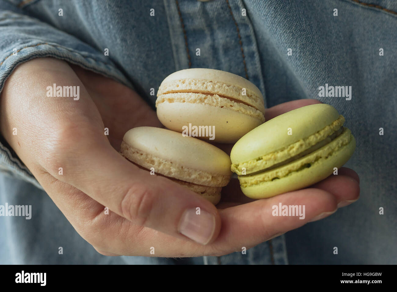 Mano che tiene la crema e verde macarons messa a fuoco selettiva Foto Stock