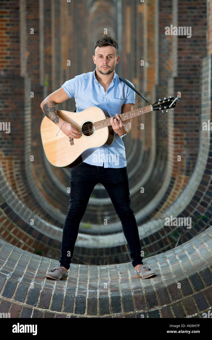 Cantante, compositore Jamie Mathias pone con la sua chitarra per un tiro al Ouse valley viadotto, Sussex, Regno Unito. Foto Stock