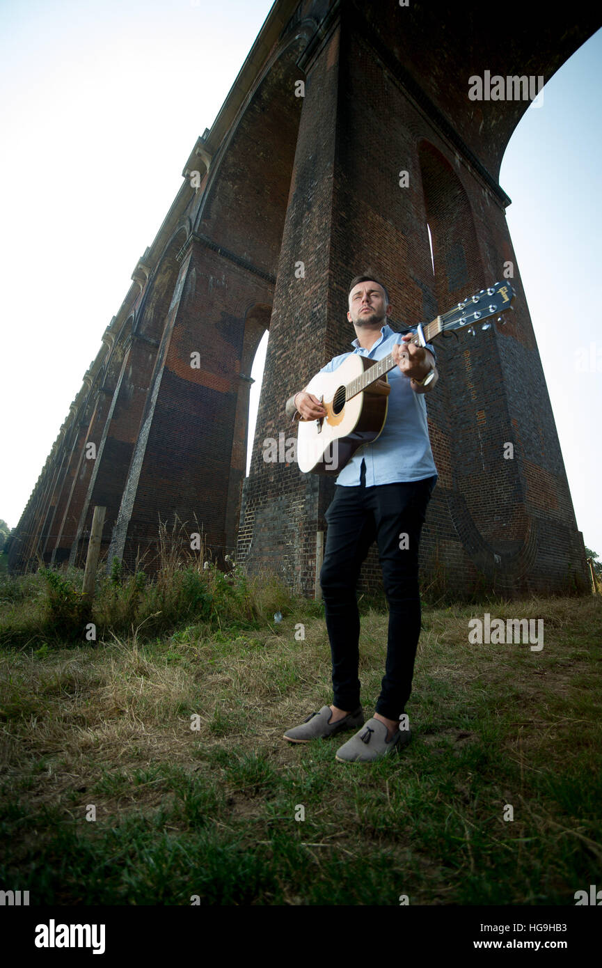 Cantante, compositore Jamie Mathias pone con la sua chitarra per un tiro al Ouse valley viadotto, Sussex, Regno Unito. Foto Stock