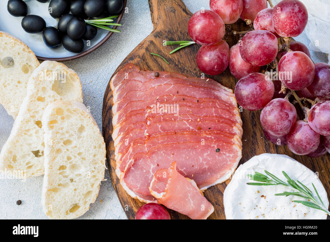 Salumi, baguette fresche, uva, il formaggio e le olive nere. Antipasti italiani set. Vista ravvicinata Foto Stock