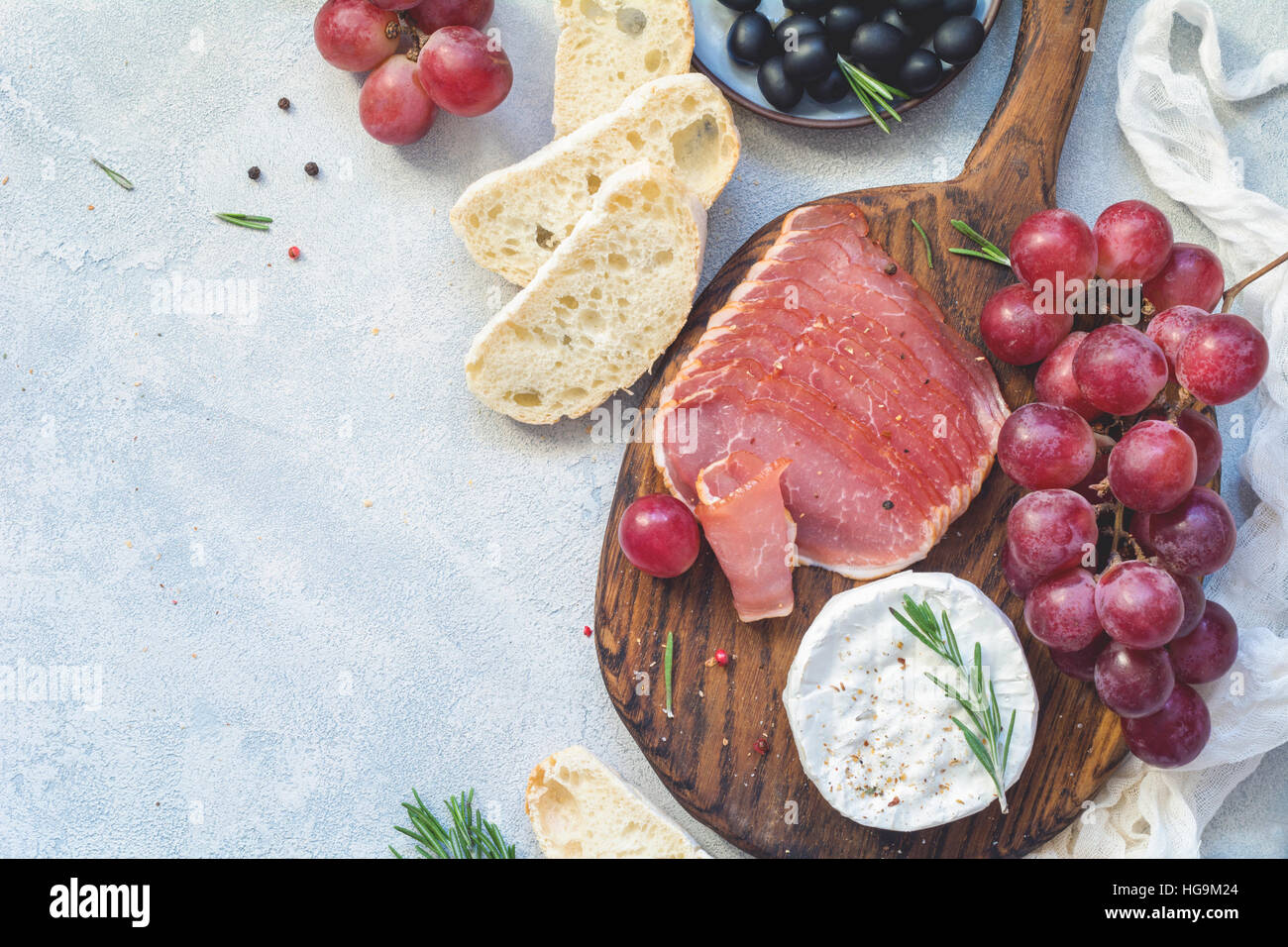 Piatto antipasto con baguette fresche, salumi, uve, il formaggio e le olive. Antipasti o il concetto di tapas. Vista superiore, spazio di copia Foto Stock