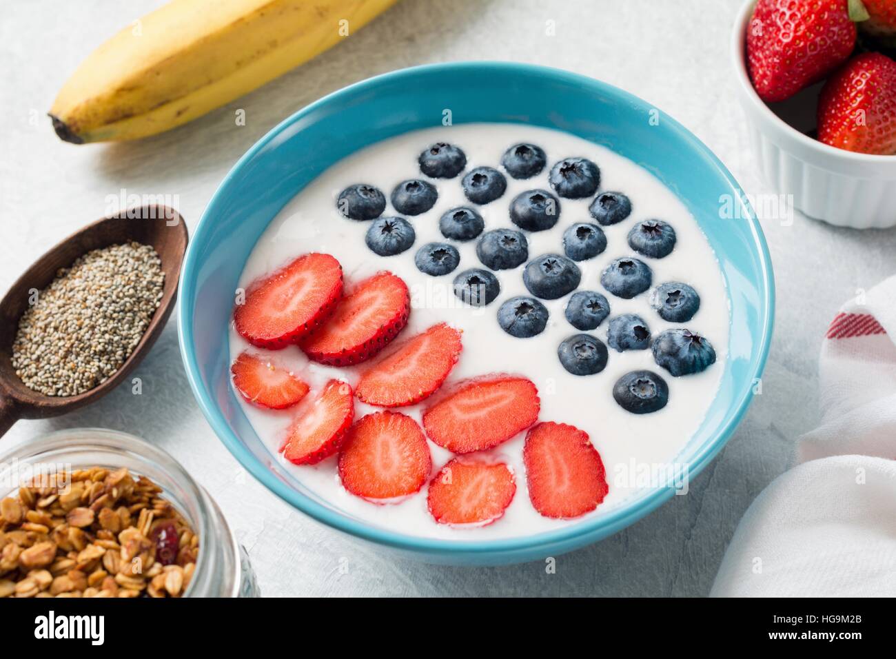 Yogurt frullato di frutta coppa con fragole e mirtilli. Vasetto di cereali fatti in casa, chia semi freschi di banana e le fragole Foto Stock