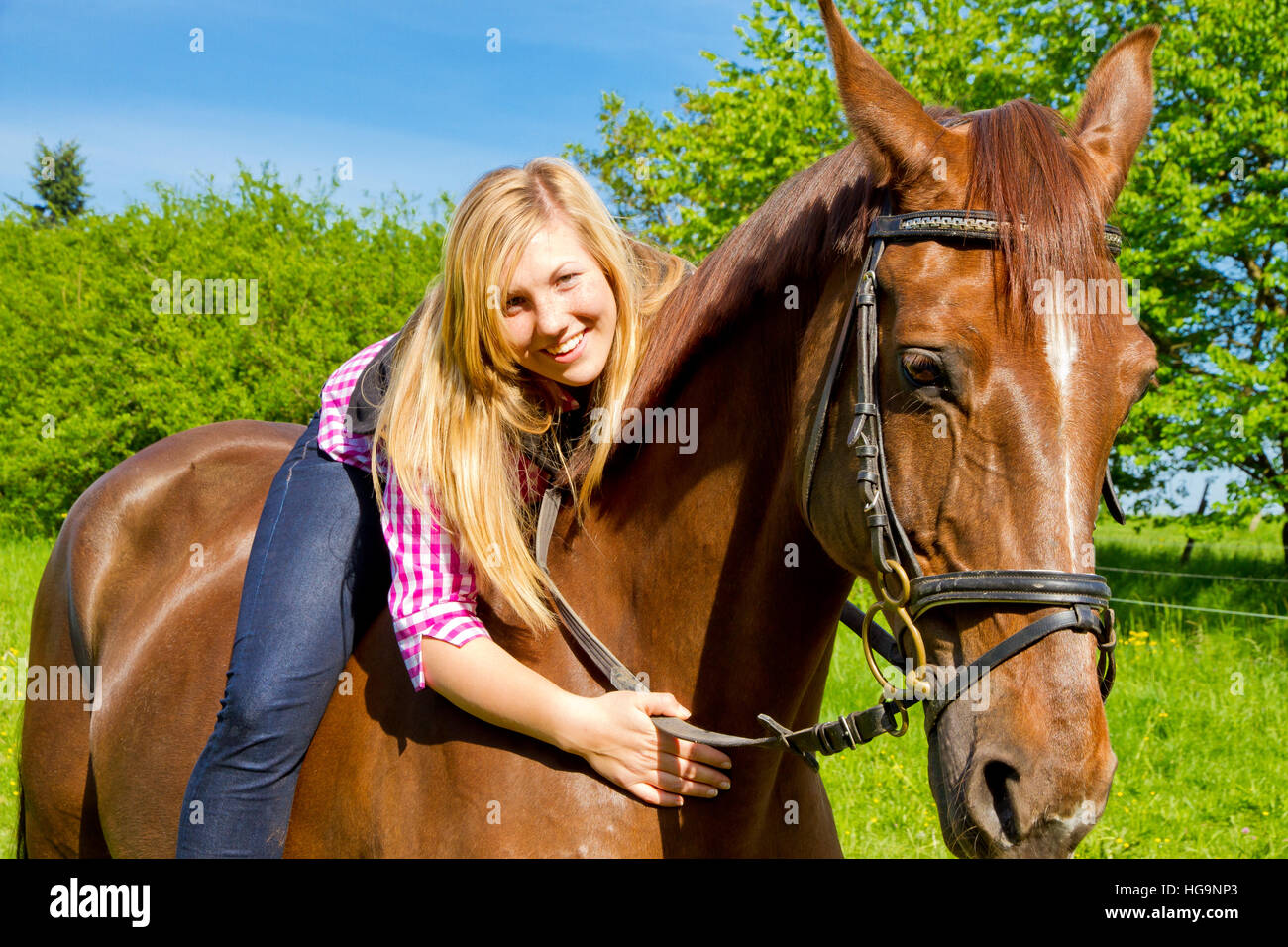 Giovane donna felice in sella il suo cavallo Foto Stock