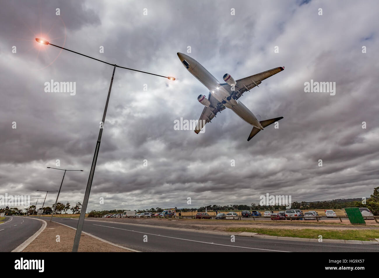 Jet del passeggero aereo volare basso nel cielo a destra sopra incandescente luci di strada durante le tempeste Foto Stock