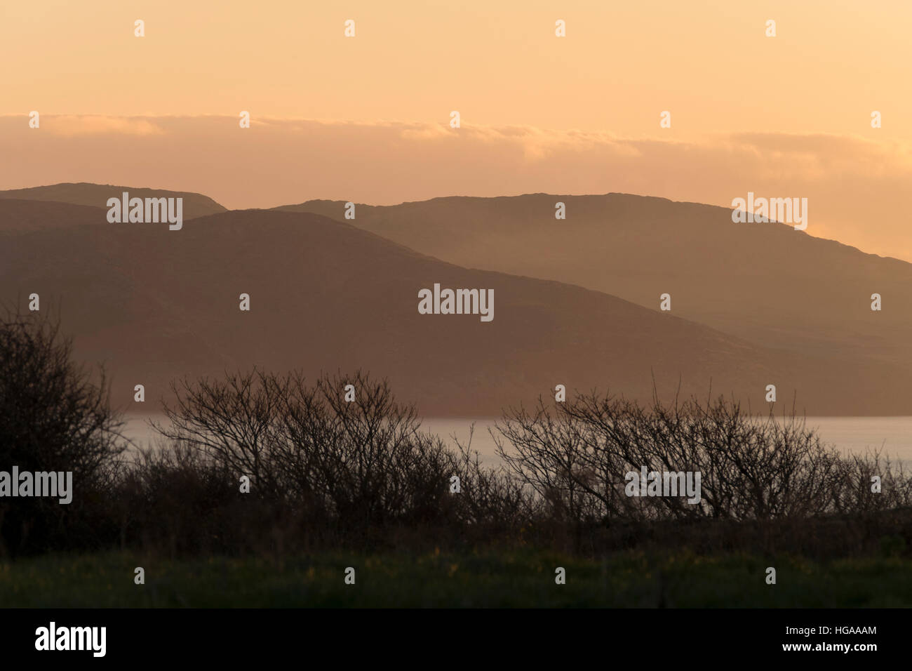Il sole tramonta sulle colline della penisola di Mizen, County Cork, Irlanda creando un bagliore dorato Foto Stock