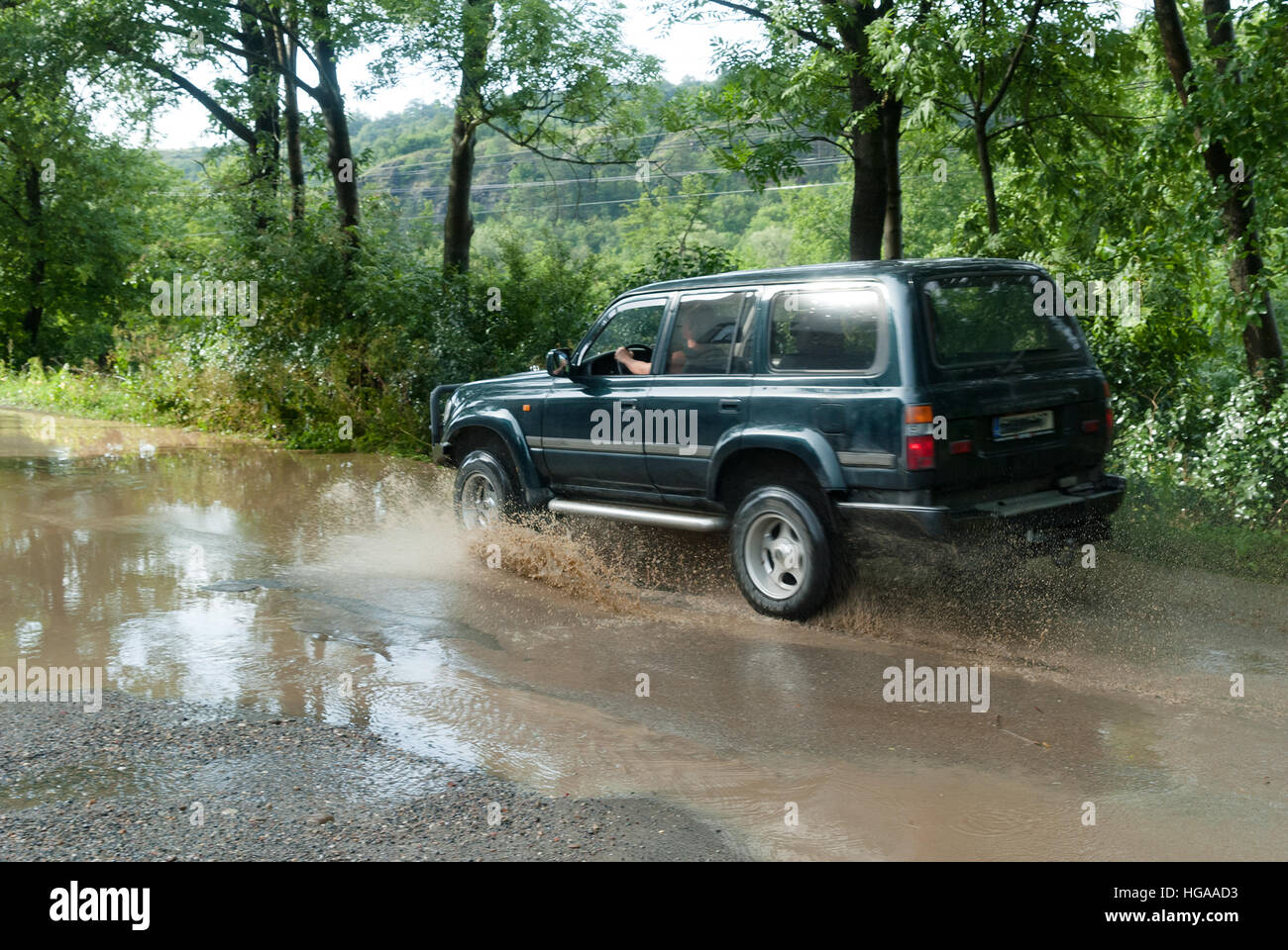 Jeep car guida attraverso il fango acqua strada allagata nella zona di campagna di Londra Foto Stock