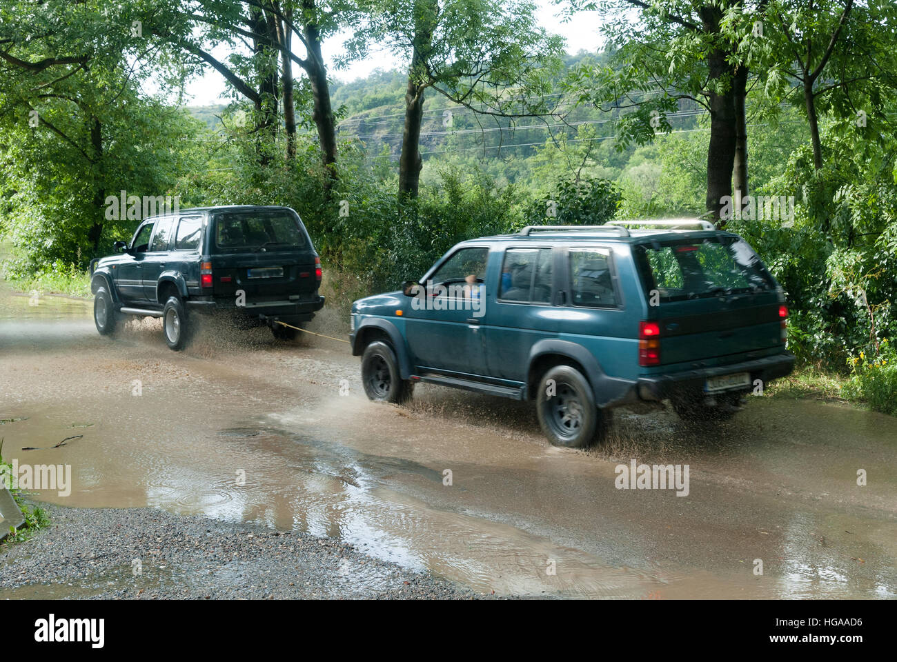 Una jeep trainato da un'altra vettura attraverso il fango acqua strada allagata Foto Stock