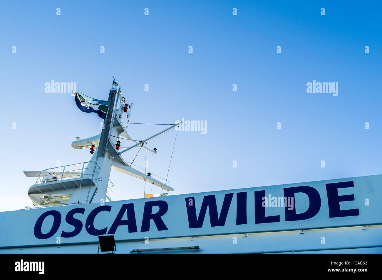 Il nome del traghetto per auto 'Oscar Wilde' scritta sulla nave con la radio e la torre del radar su un blu chiaro giorno con copia spazio. Foto Stock