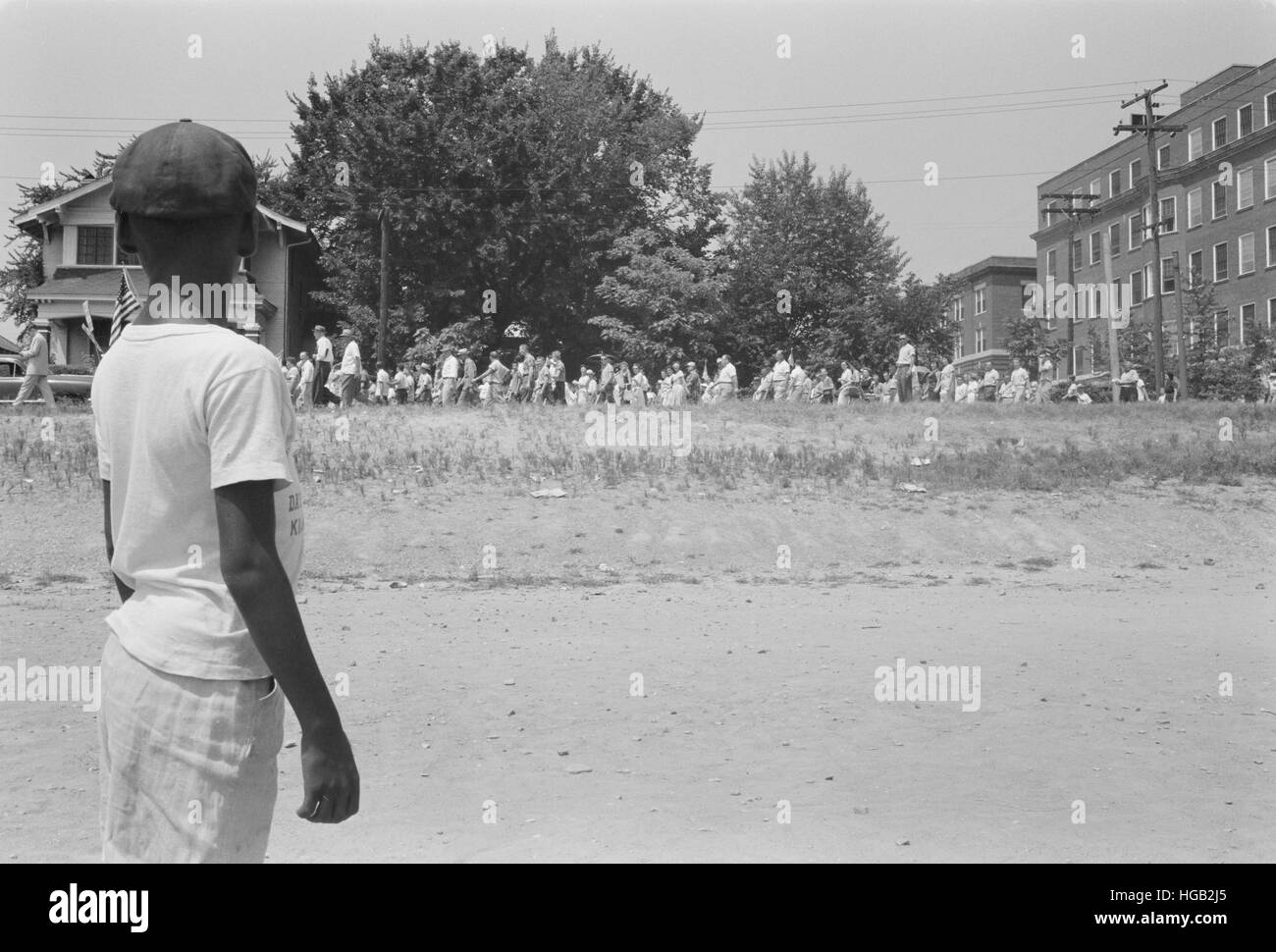 Un giovane africano American boy orologi di una folla in marcia da a Little Rock Central High, 1959. Foto Stock