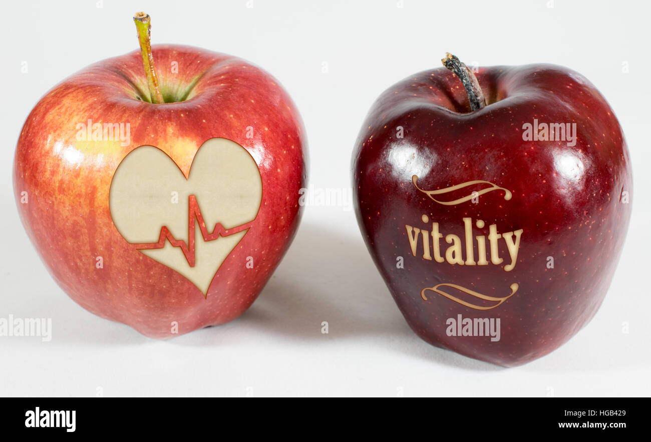 2 mele rosse su uno sfondo bianco, 1 mela reca la scritta vitalità altri un cuore con il battito del cuore Foto Stock