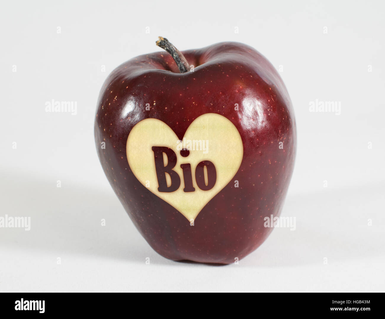 1 rosso fresco apple con un cuore e l'etichetta bio su sfondo bianco Foto Stock