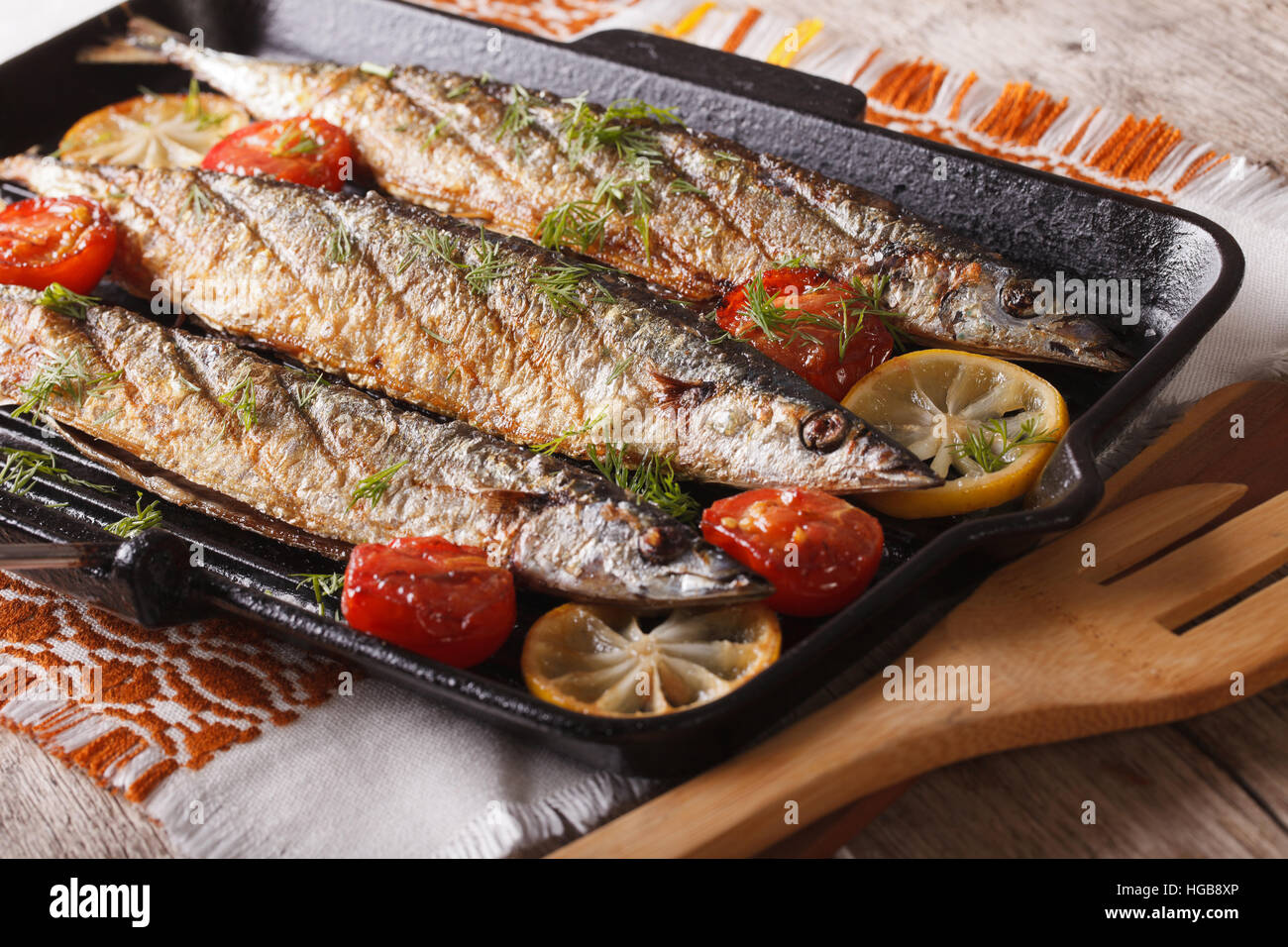 Appetitose grigliate di pesce con verdure su una padella per grigliare su un tavolo di close-up orizzontale. Foto Stock