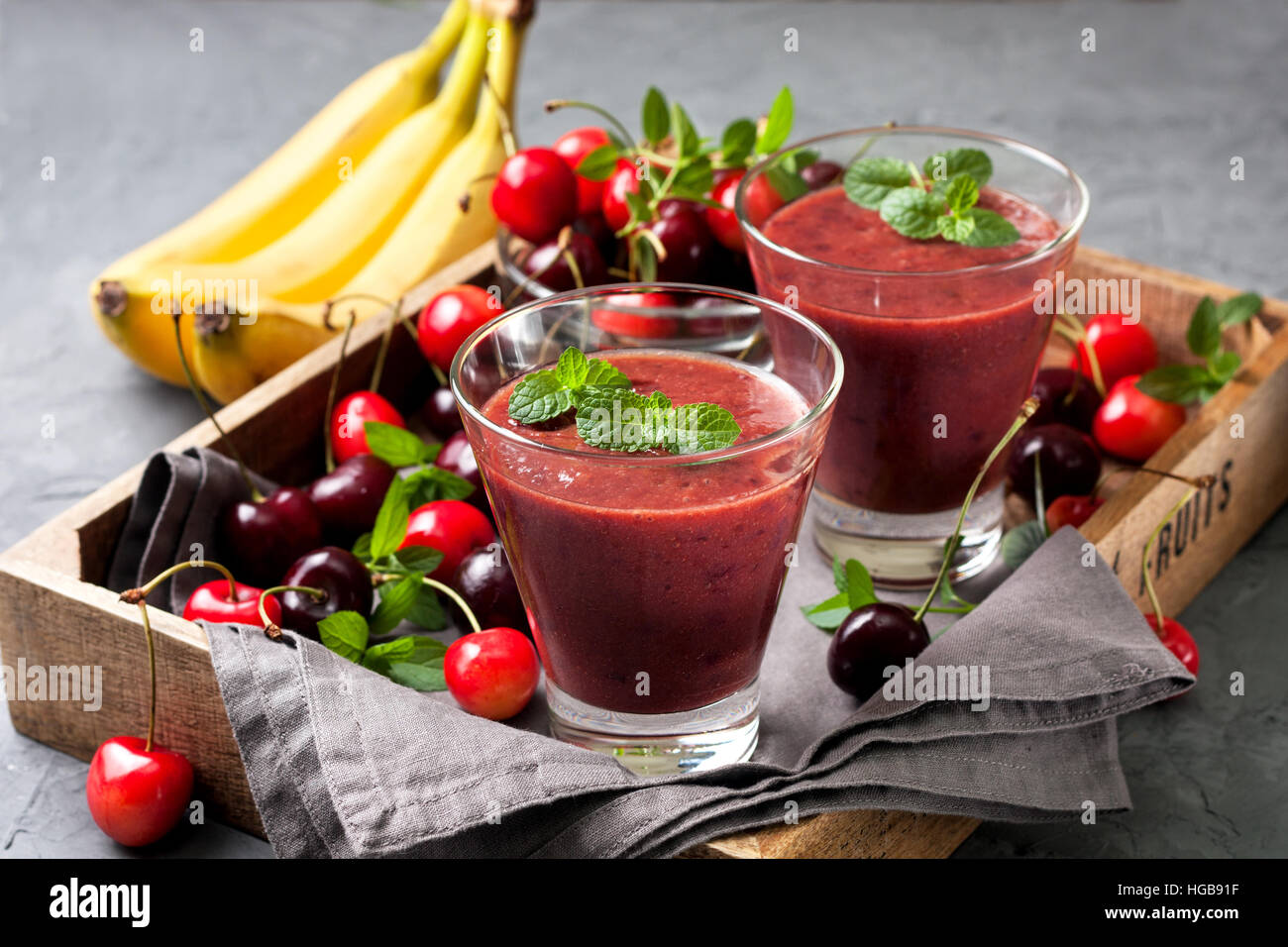 Smoothie con ciliegia e banana in un vetro, una miscela di ciliegie dolci su sfondo di calcestruzzo Foto Stock