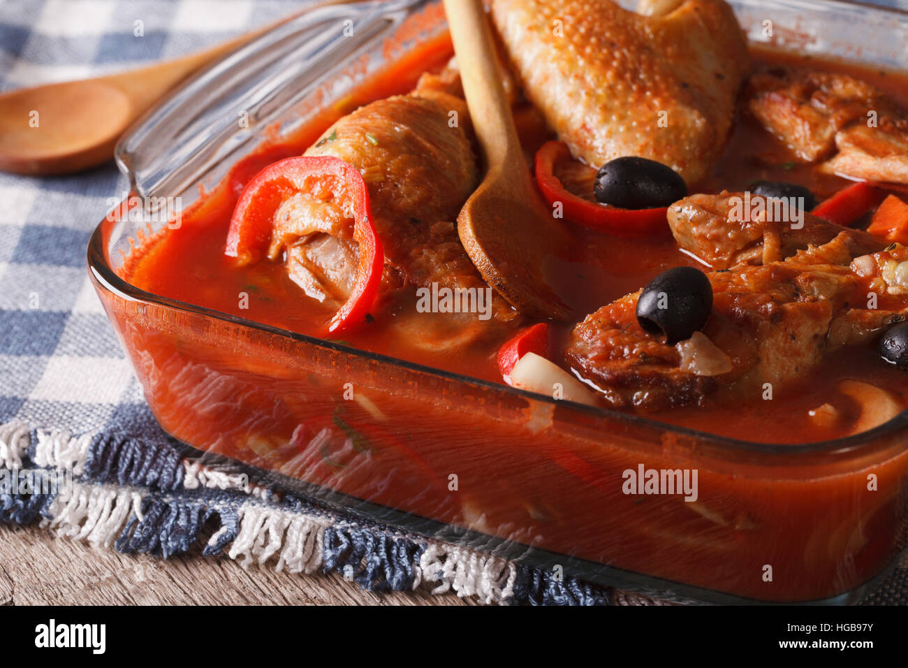 Spezzatino di pollo in salsa di pomodoro con olive vicino fino in una ciotola di vetro orizzontale. Foto Stock