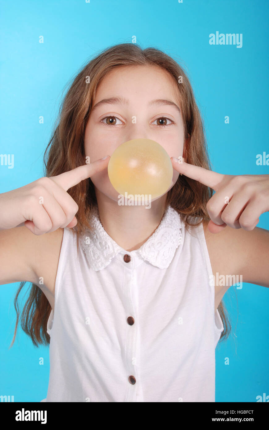 Ragazza a soffiare una grande bolla bubble gum isolato su blu Foto Stock