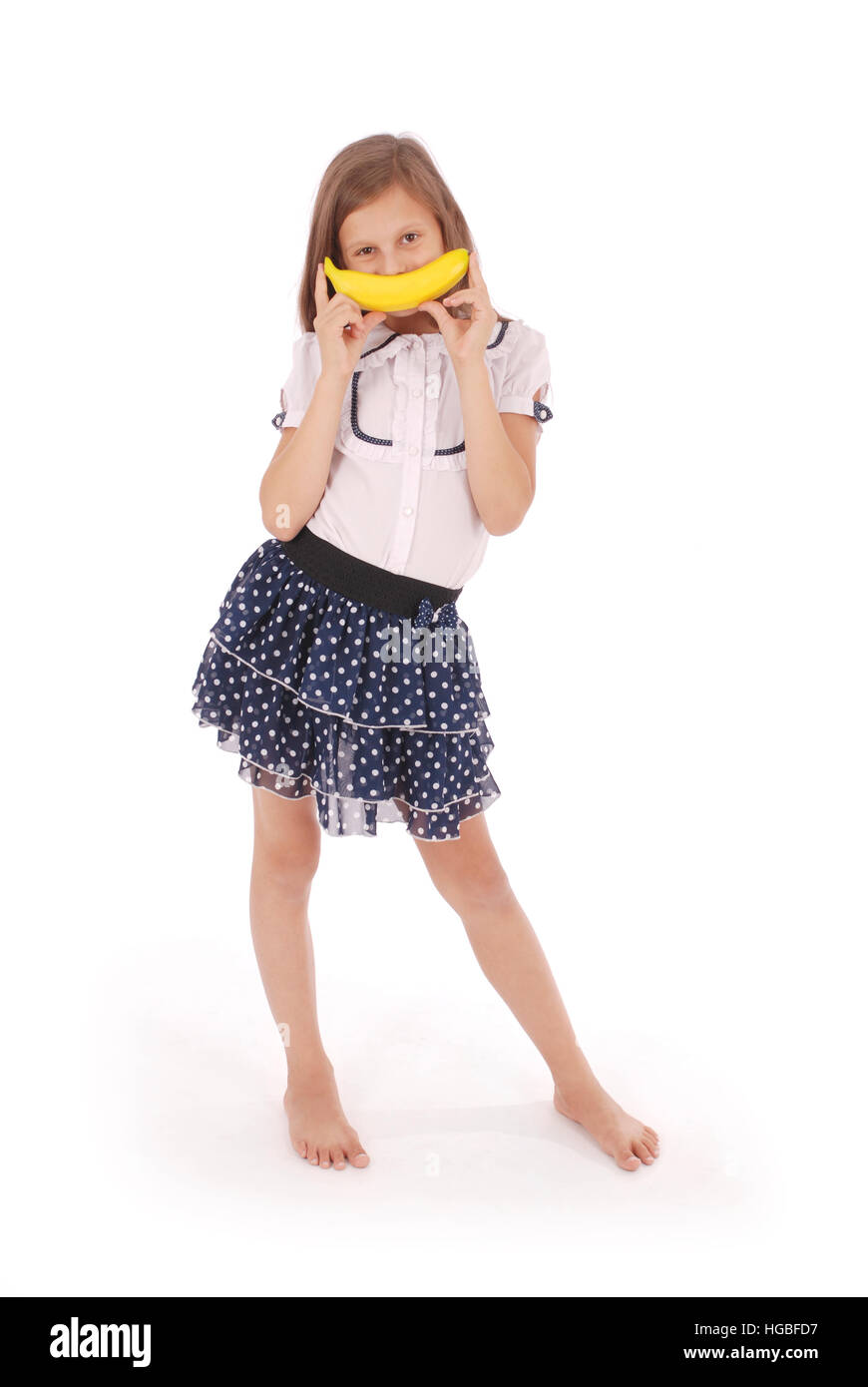 Una giovane ragazza può contenere fino a banana per la sua bocca, imitando un sorriso. Isolato su sfondo bianco Foto Stock