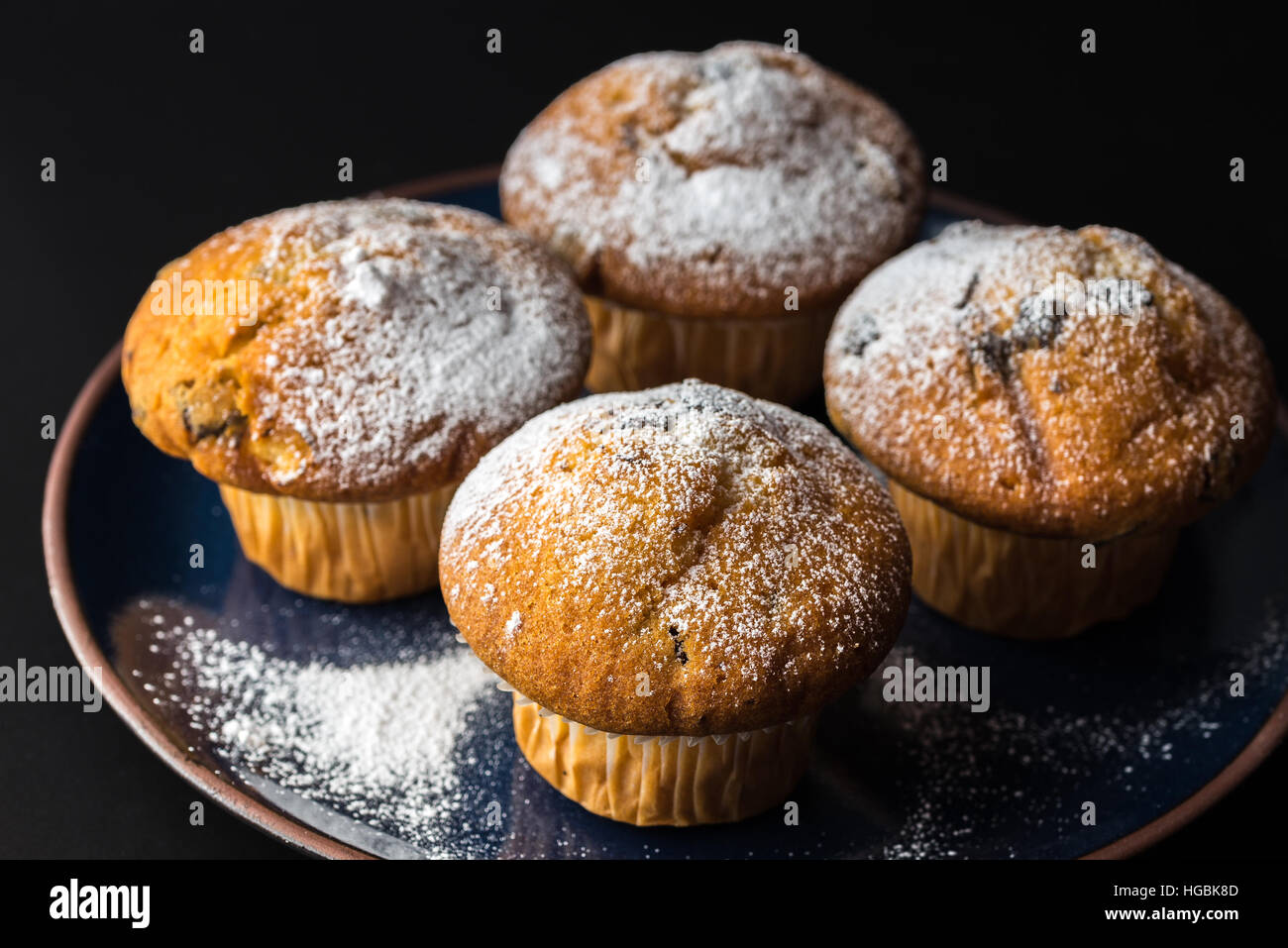 Muffin al cioccolato con zucchero a velo sul blu scuro piastra. Foto Stock