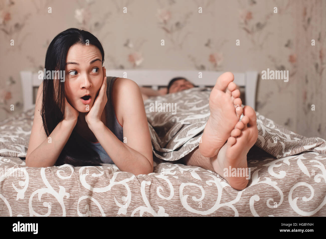 Sorpreso donna con il suo uomo disteso a letto. Foto Stock