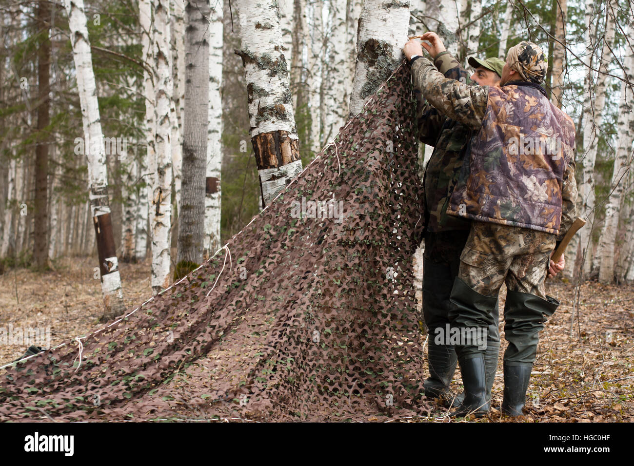 Due cacciatori tirare camouflage netting Foto Stock
