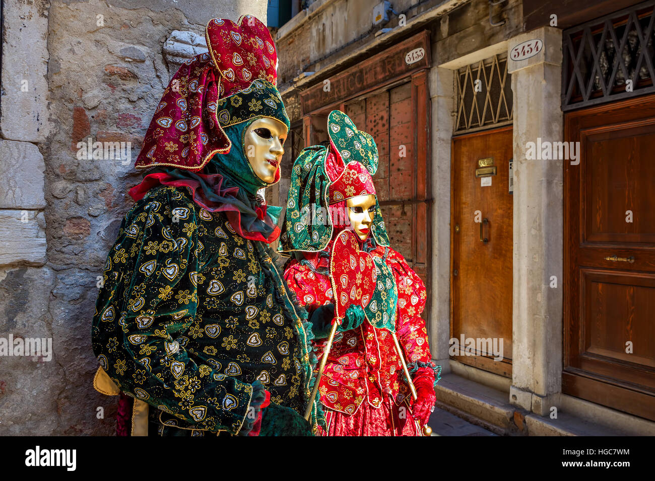 Coppia di partecipanti in abiti colorati e maschere sulla vecchia strada di Venezia durante il tradizionale carnevale famoso. Foto Stock