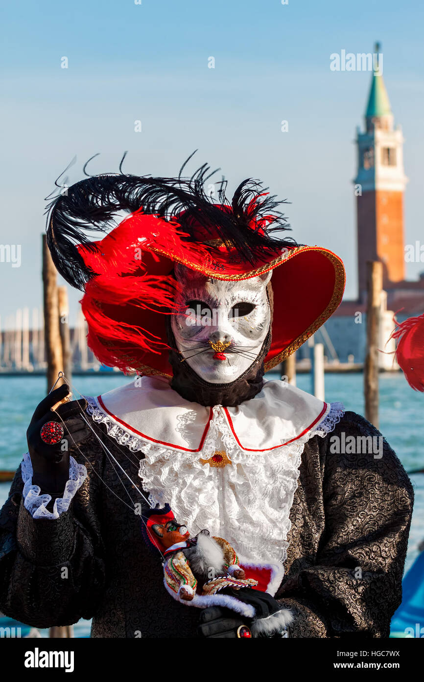 Partecipante in costume colorato e la maschera di gatto nella parte anteriore della chiesa di San Giorgio Maggiore durante il tradizionale carnevale famoso. Foto Stock