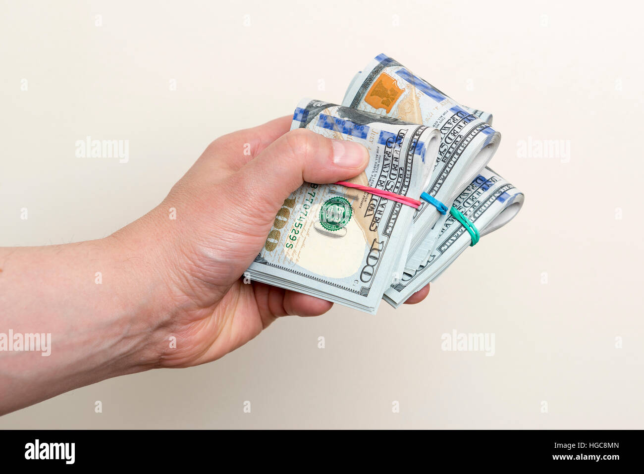 Maschio di mano azienda di confezioni di un centinaio di dollari di banconote Foto Stock