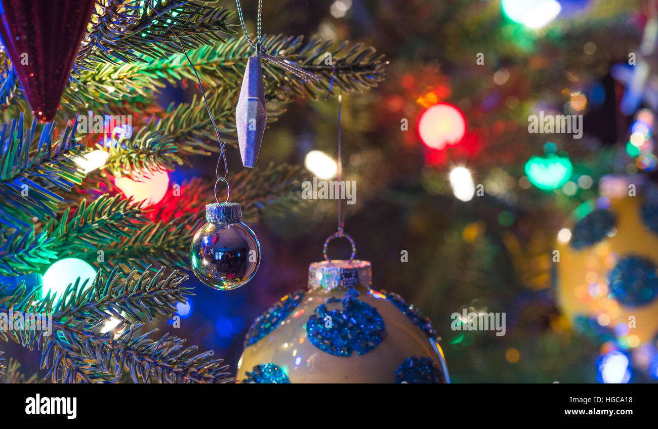 Addobbi per l'albero di Natale. Giallo, finitura brillante orb con i cerchi blu, bagliori, circondato da luminose,vibrante luci multicolori Foto Stock