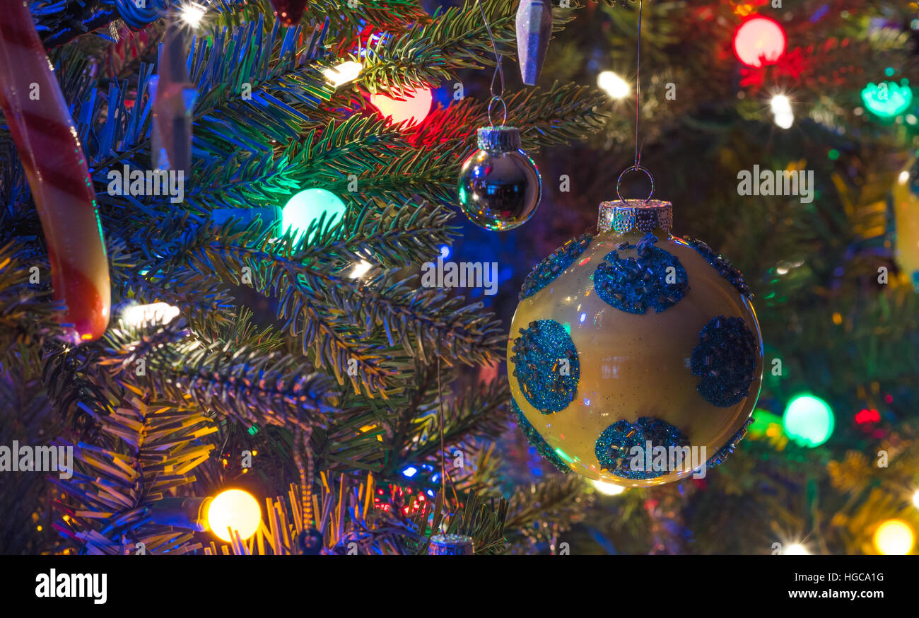 Addobbi per l'albero di Natale. Giallo, finitura brillante orb con i cerchi blu, bagliori, circondato da luminose,vibrante luci multicolori Foto Stock