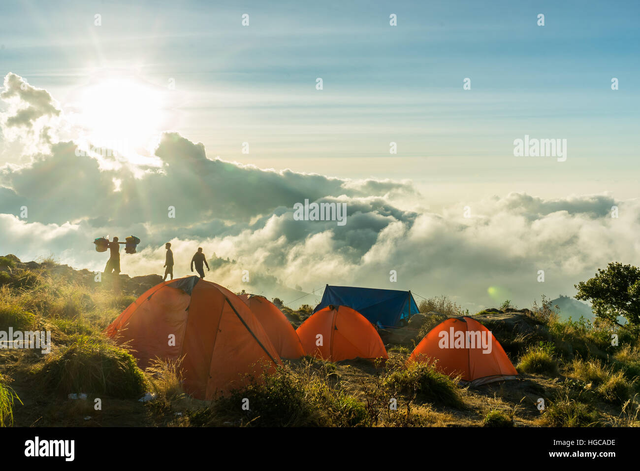 Campo in tenda sul bordo del cratere del monte rinjani, lombok, Indonesia. Sun è l'impostazione nelle nuvole, tende glow arancio brillante. Foto Stock