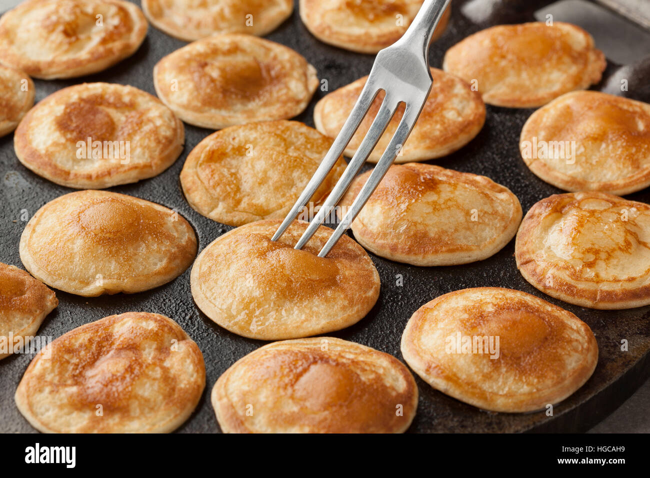 Cottura in forno olandese mini pancake chiamato poffertjes in una padella speciale pan Foto Stock