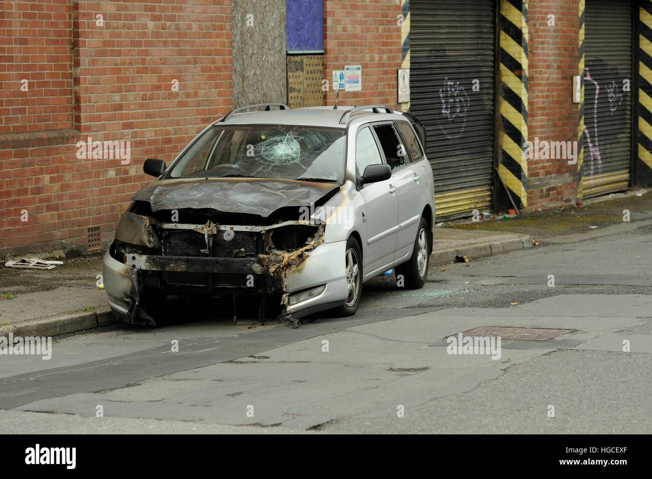 Bruciata auto con parabrezza fracassato dal lato della strada in una zona industriale di una città Foto Stock