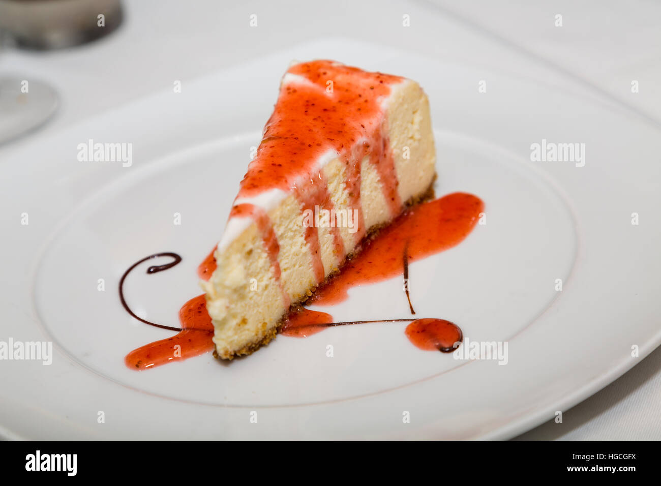 Fetta di Cheesecake con salsa di fragole e cioccolato Swirl turbolenza sulla piastra bianca Foto Stock