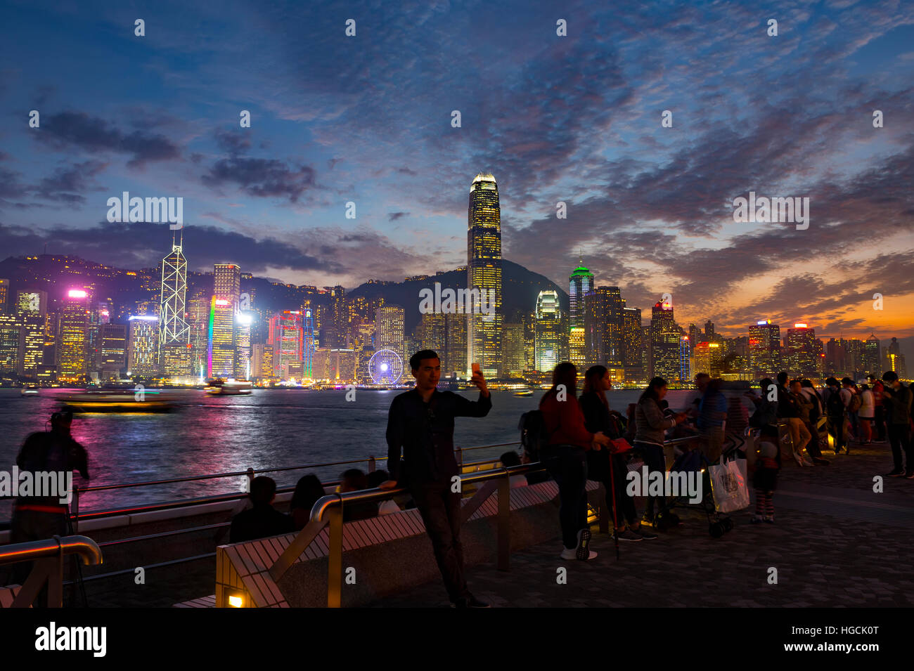 Il famoso quartiere Tsim Sha Tsui promenade e turisti che si godono la sera il panorama dell'Isola di Hong Kong, Hong Kong, Cina. Foto Stock