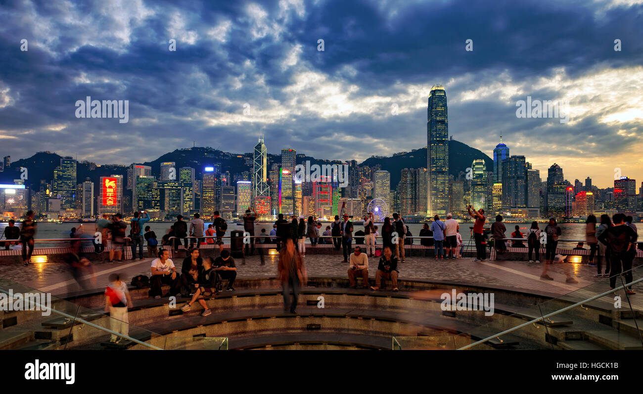 Il famoso quartiere Tsim Sha Tsui promenade e turisti che si godono la sera il panorama dell'Isola di Hong Kong, Hong Kong, Cina. Foto Stock
