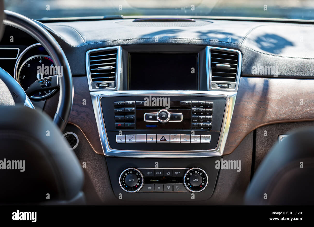 Per interni auto di lusso. Il beige e comodi posti a sedere, volante, cruscotto, climatizzatore, tachimetro, display, decorazioni di legno. Foto Stock