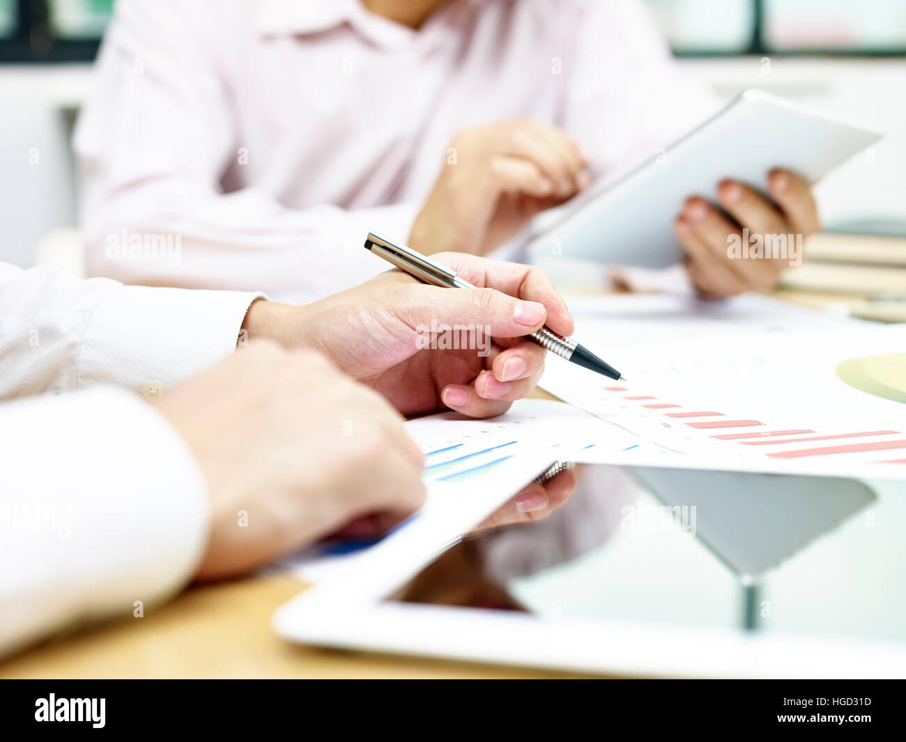 La gente di affari di analizzare e discutere le prestazioni delle vendite e le tendenze in ufficio utilizzando compresse e relazioni. Foto Stock